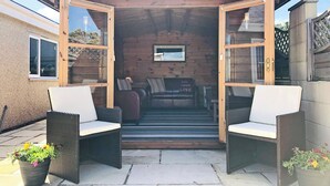 A wooden structure with an open entrance, wicker chairs, a bench, and a potted plant. - 3 bedroom accommodation in Aberdaron (Aberdaron)