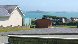 A coastal view with a building, a small wooden structure, and a stone wall. - 3 bedroom accommodation in Aberdaron (Aberdaron)