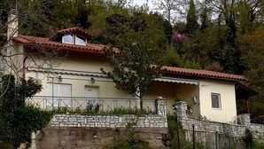 A two-story house with a stone wall and a red-tiled roof. - Plataniotissa Mansion (Plataniotissa)