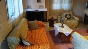 A cozy living room with a sofa, armchair, and a small table with a lamp. - Plataniotissa Mansion (Plataniotissa)