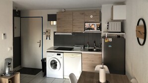 Una cocina compacta equipada con lavadora, microondas y refrigerador.
