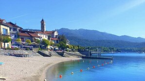 Una playa con aguas cristalinas, un muelle y edificios al fondo.