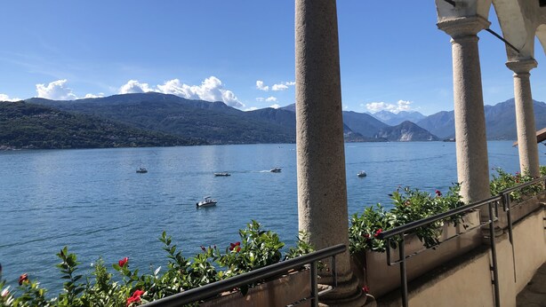 Vista de un lago con barcos, rodeado de montañas y un cielo despejado.