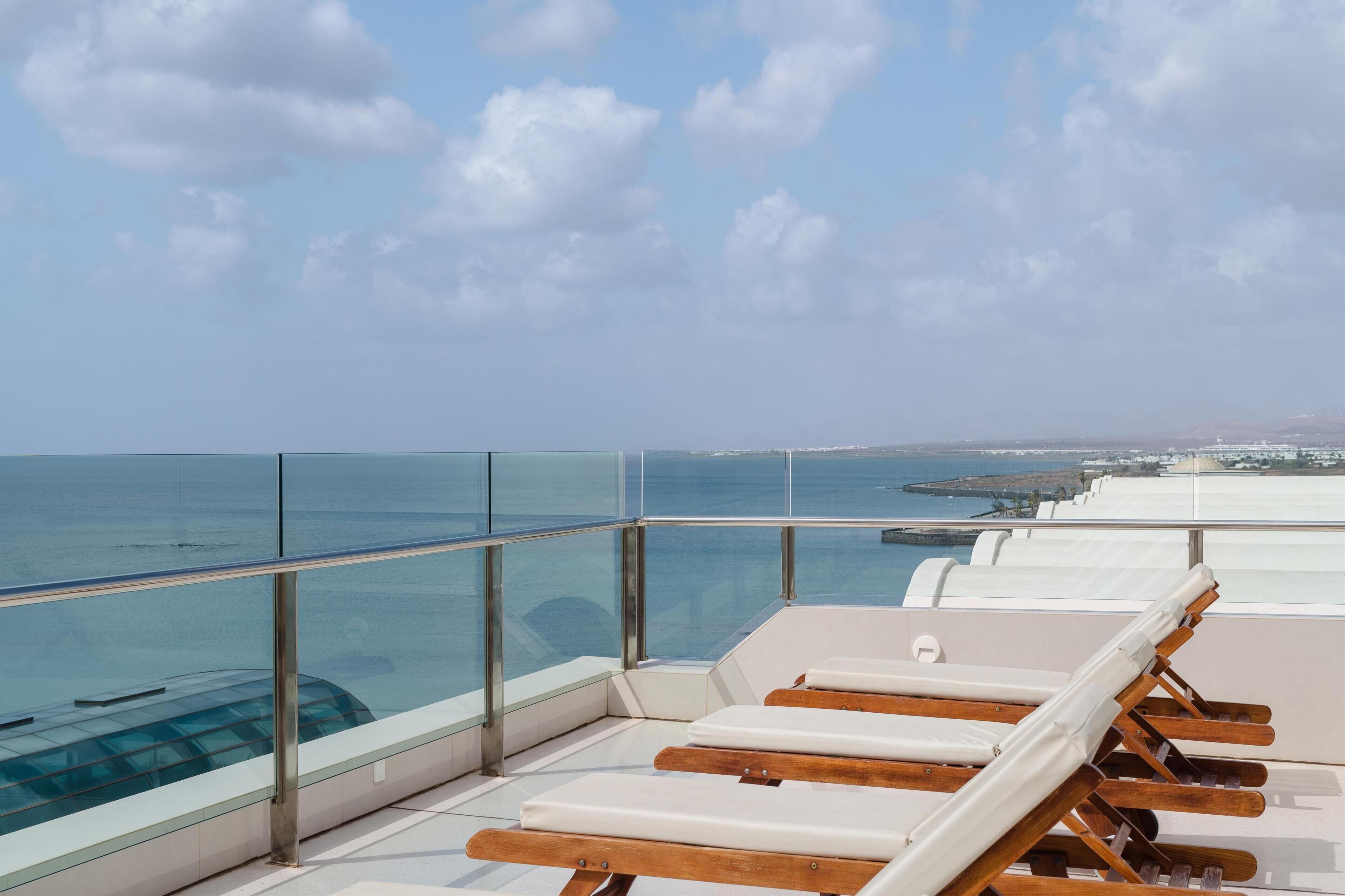 A rooftop terrace with lounge chairs overlooking the sea.
