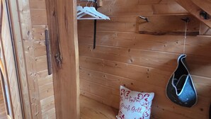 A wooden interior with a bench, a hanging shoe, and a white pillow with red text.