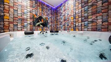 Un espace spa agrémenté d’un mur en pierre, d’un bain à remous et d’un porte-serviettes.
