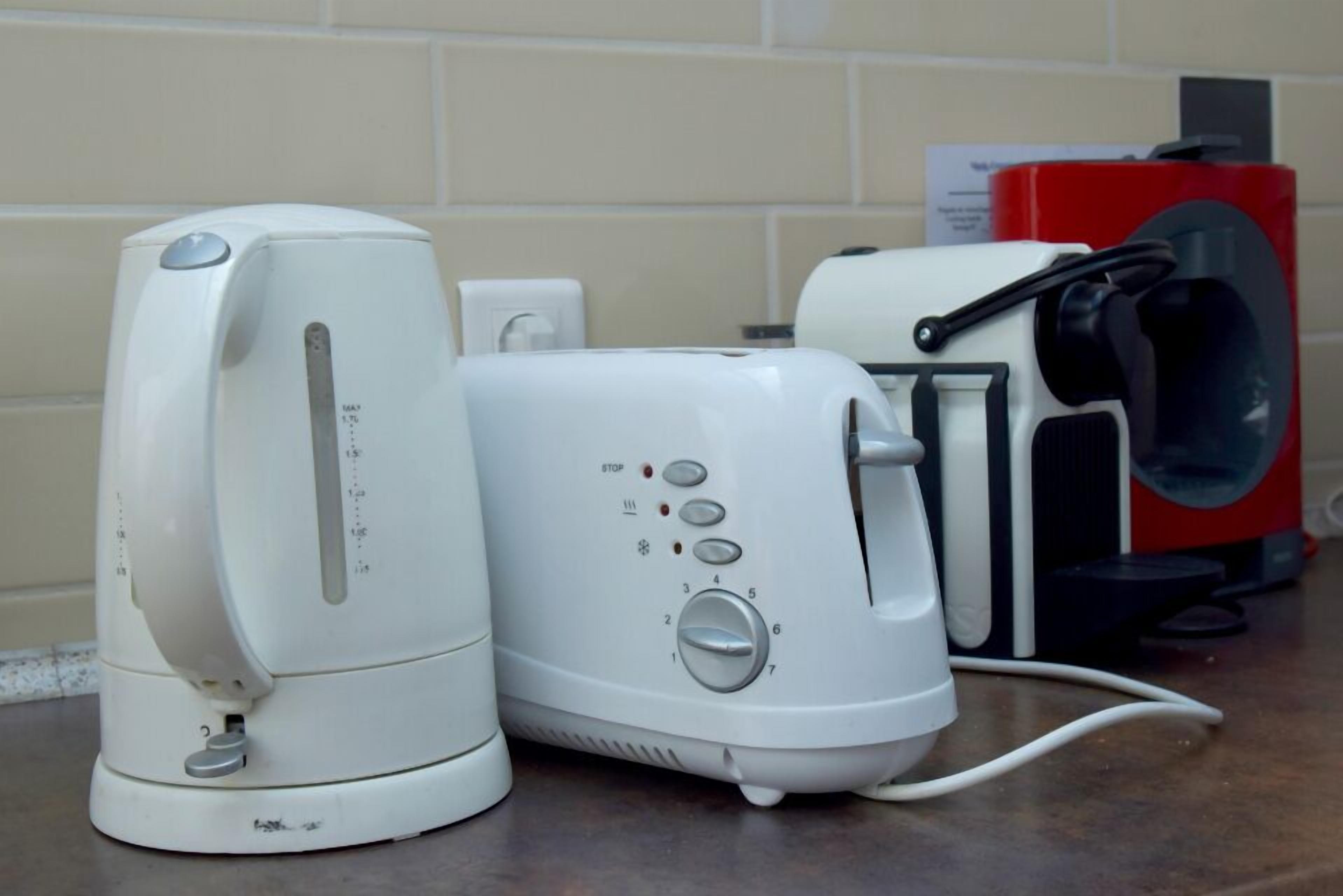 A kitchen with a white electric kettle, a toaster, and a red coffee machine on the counter.