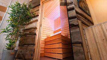 L’intérieur d’une cabane en rondins, avec un banc en bois, une plante en pot et une porte en bois.