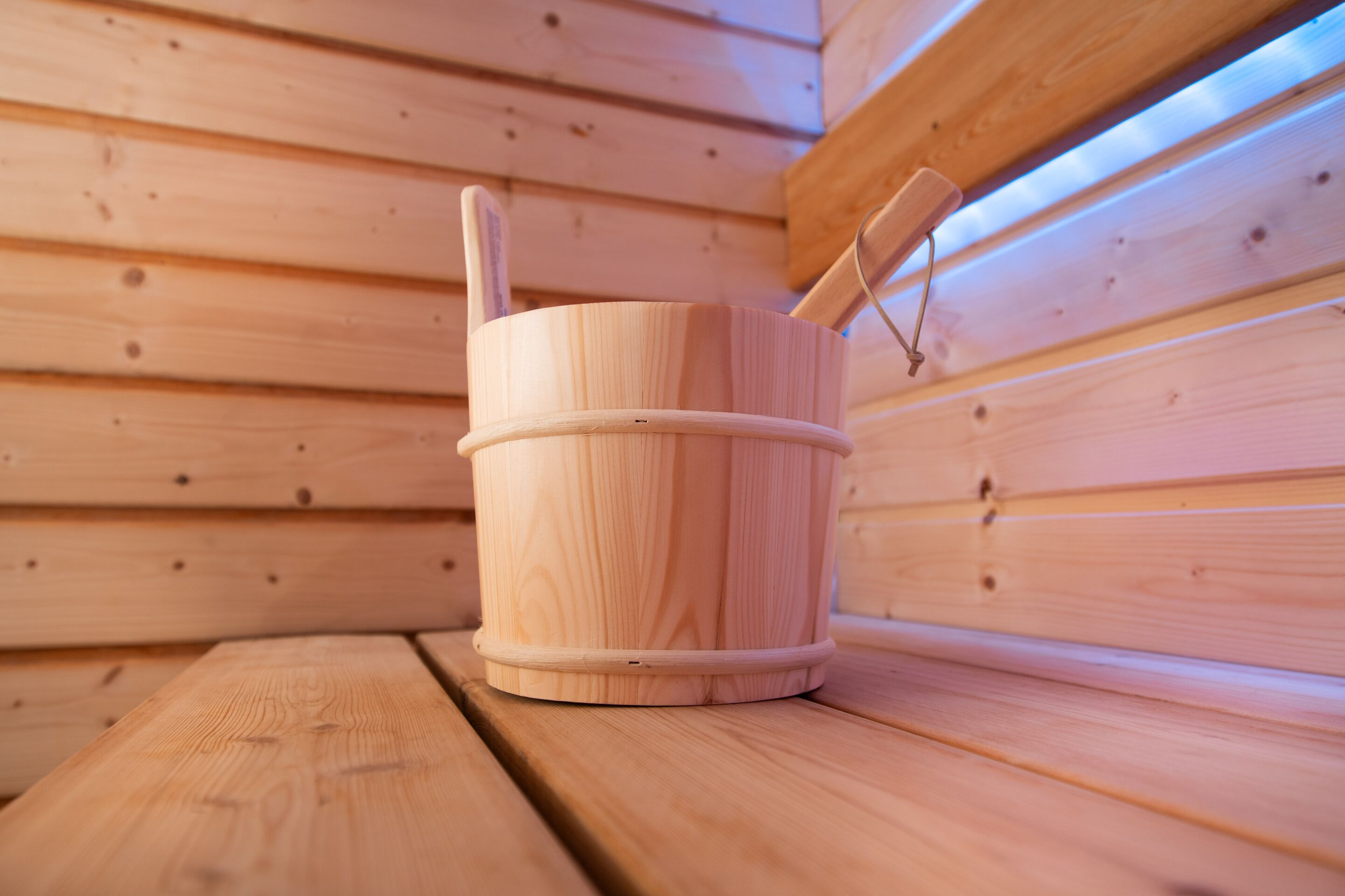 Een houten sauna met een houten emmer en een houten bank.