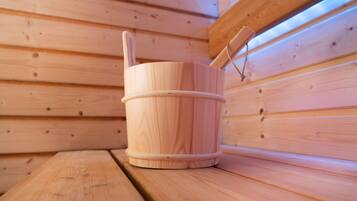 Een houten sauna met een houten emmer en een houten bank.