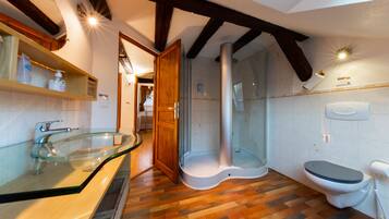 Een badkamer met een glazen douchecabine, toilet en een wastafel met een houten blad.