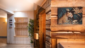 Un interior de madera con una estantería de madera, una planta en maceta y un cuadro de un leopardo.