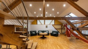 Un loft amplio con suelo de madera, una mesa redonda central y una hamaca.
