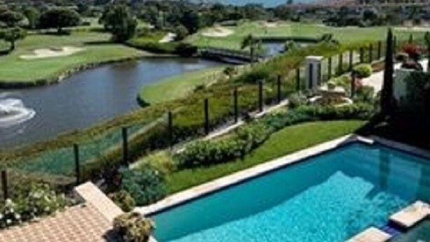 En swimmingpool med udsigt til en golfbane og en flod.