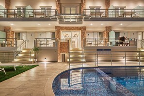 Een hotel met meerdere verdiepingen, een zwembad, terras en een gevel van natuursteen.