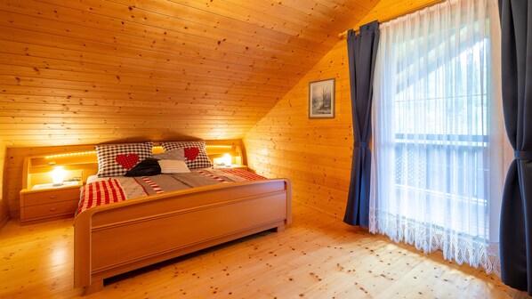 A cozy bedroom with a wooden ceiling, a bed with checkered bedding, and a nightstand with a lamp. - Idyllic vacation home in a quiet location (Sittersdorf)