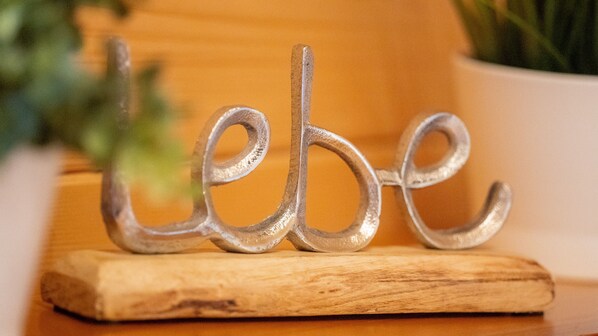 A decorative metal sign with the word "Lebe" on a wooden base.