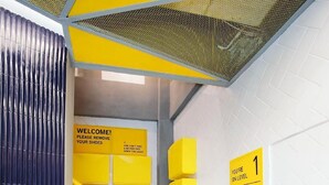 A staircase with yellow handrails and signs, including a welcome sign and a level indicator.