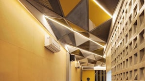 A narrow hallway with a yellow wall, a white tiled wall, and a wooden table with stools.