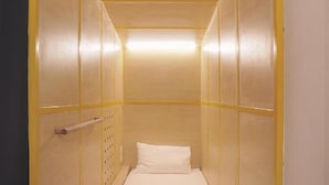 A narrow, single-bed room with a wooden headboard and a bedside table.