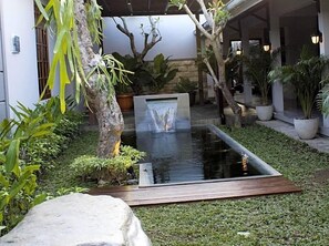 A garden with a water feature, potted plants, and a stone structure. - Grand Marto Hotel (Yogyakarta)