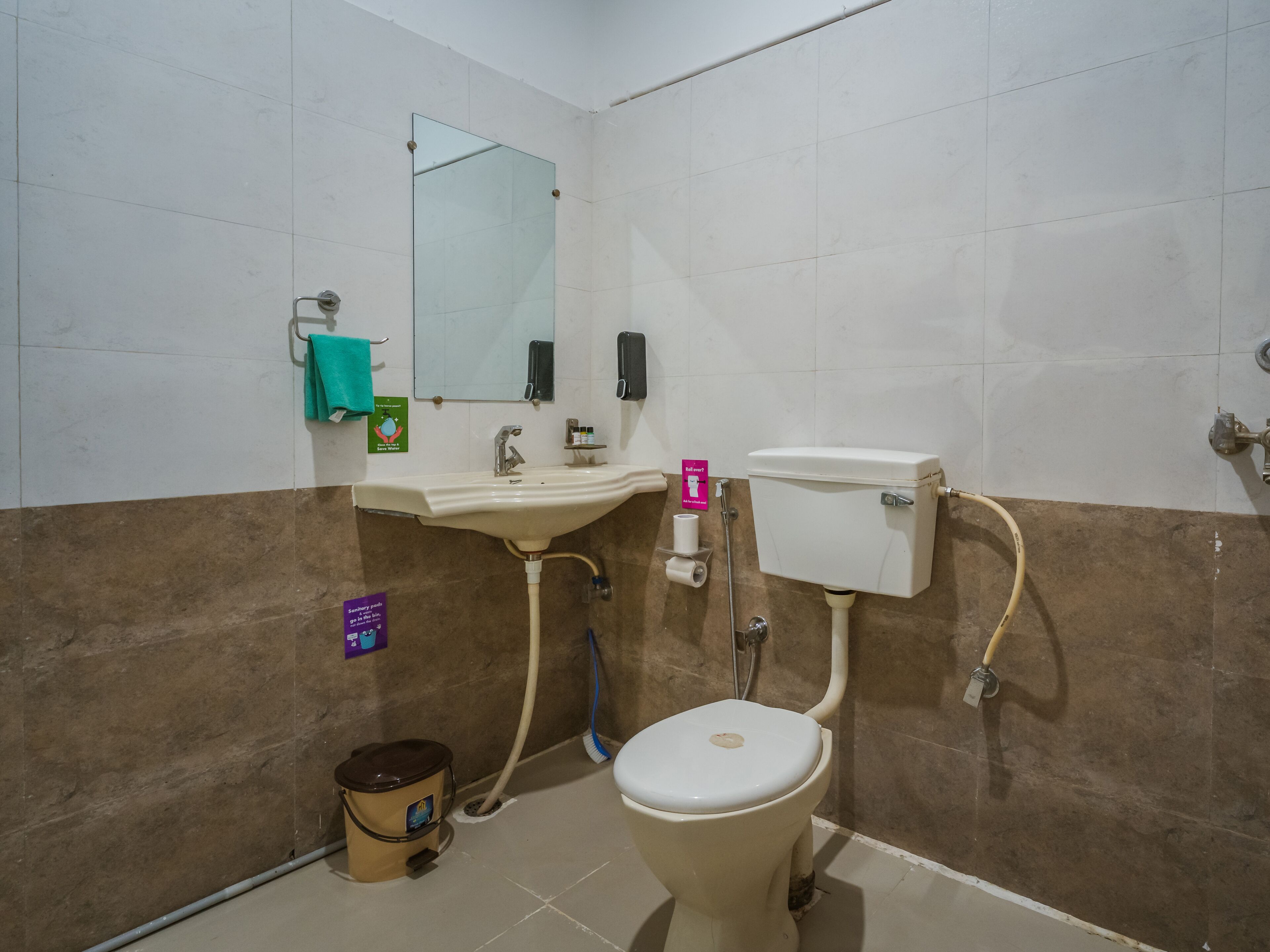 Un baño con inodoro, lavabo, espejo y secador de manos.