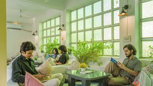 Un área de descanso moderna con ventanas amplias, disposición de asientos e plantas de interior.