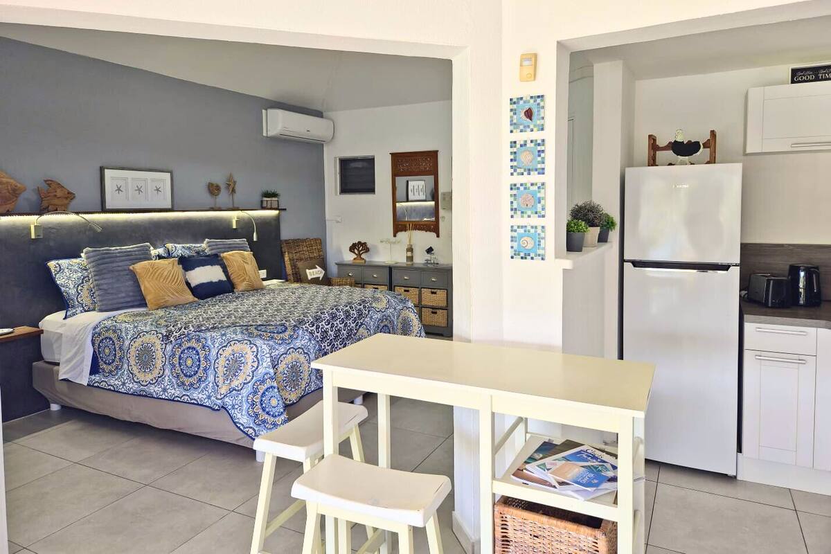 A compact bedroom with a bed, bedside table, and a small kitchenette.