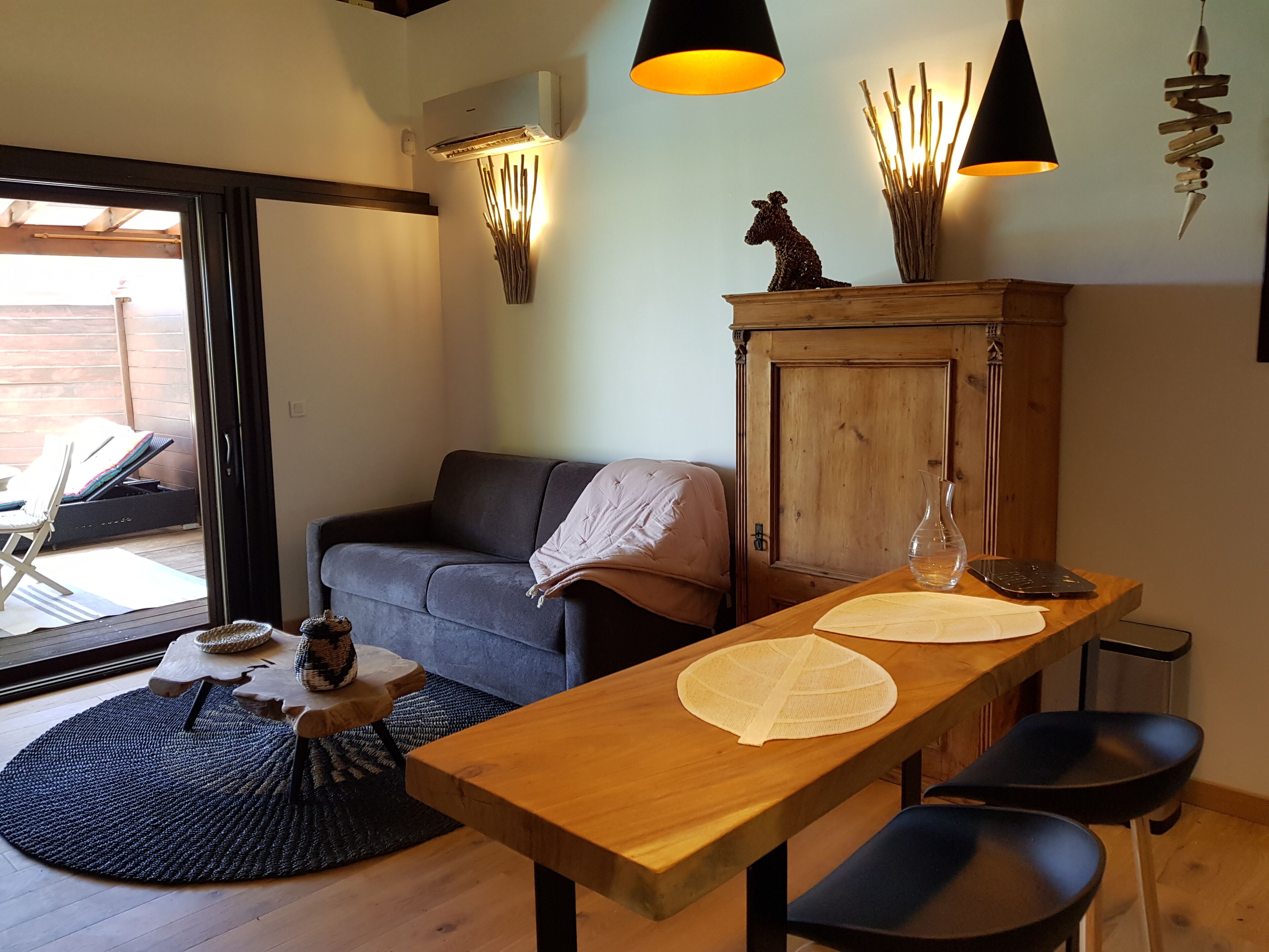 Una sala de estar acogedora con un sofá, una mesa de madera con sillas, un aparador y un adorno de pared.