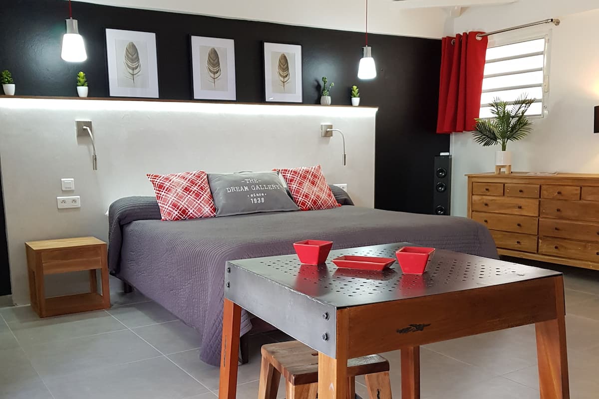 A modern bedroom with a bed, bedside table, and a small wooden stool.