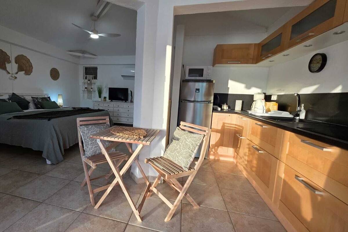 A modern apartment with a dining area, kitchen, and a bedroom.