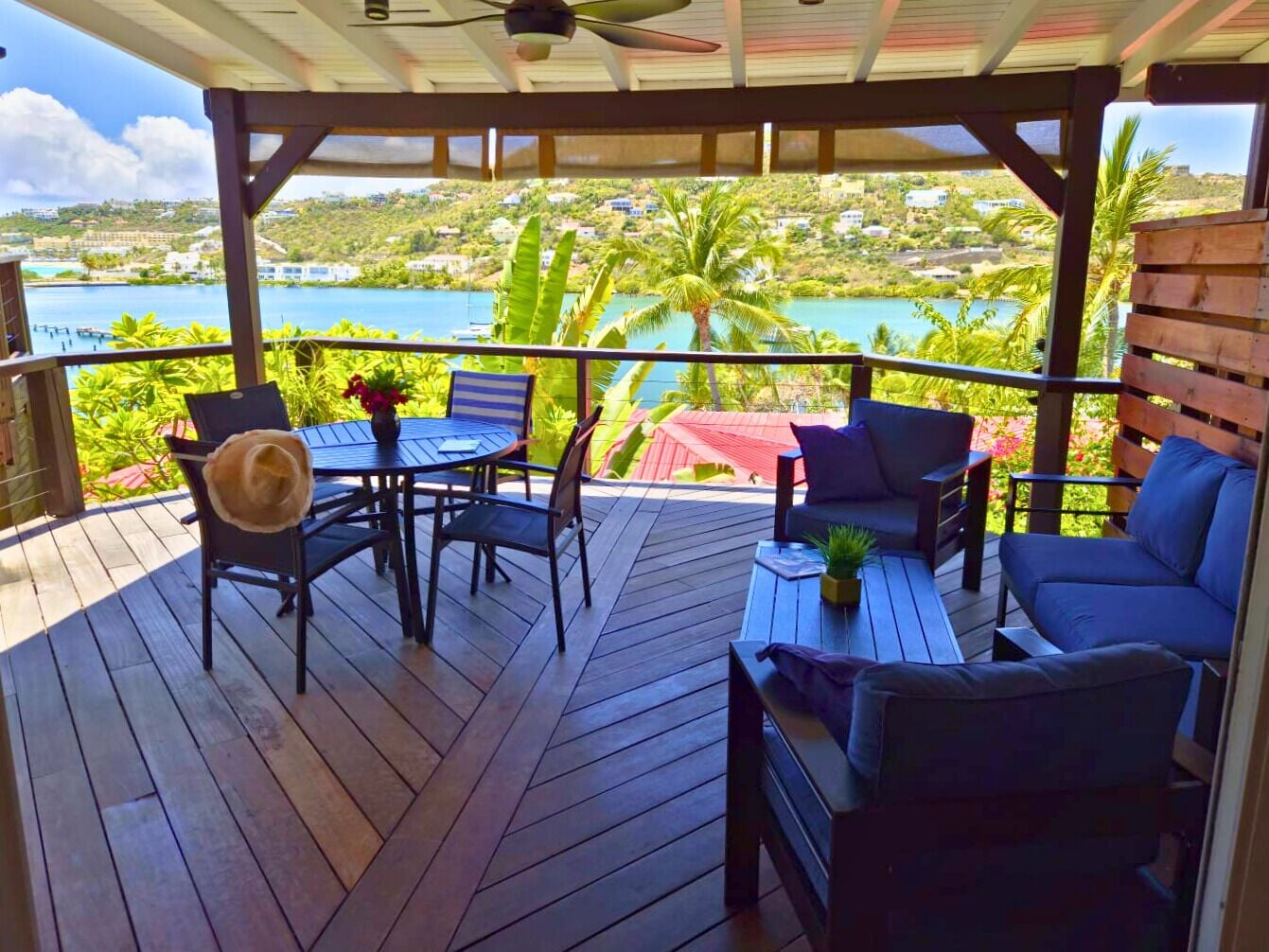Un espace extérieur abrité, doté d’une terrasse en bois, d’une table avec des chaises et d’un canapé.