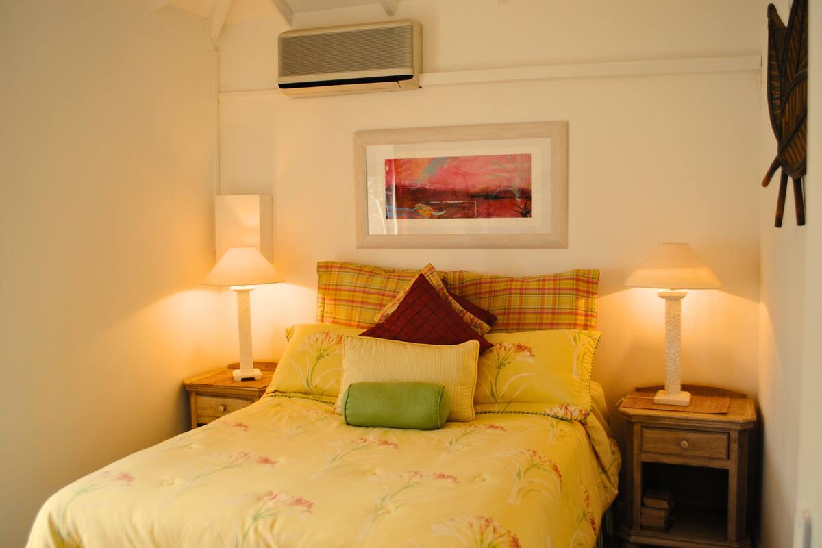 A bed with floral bedding, two bedside lamps, and a framed picture on the wall.