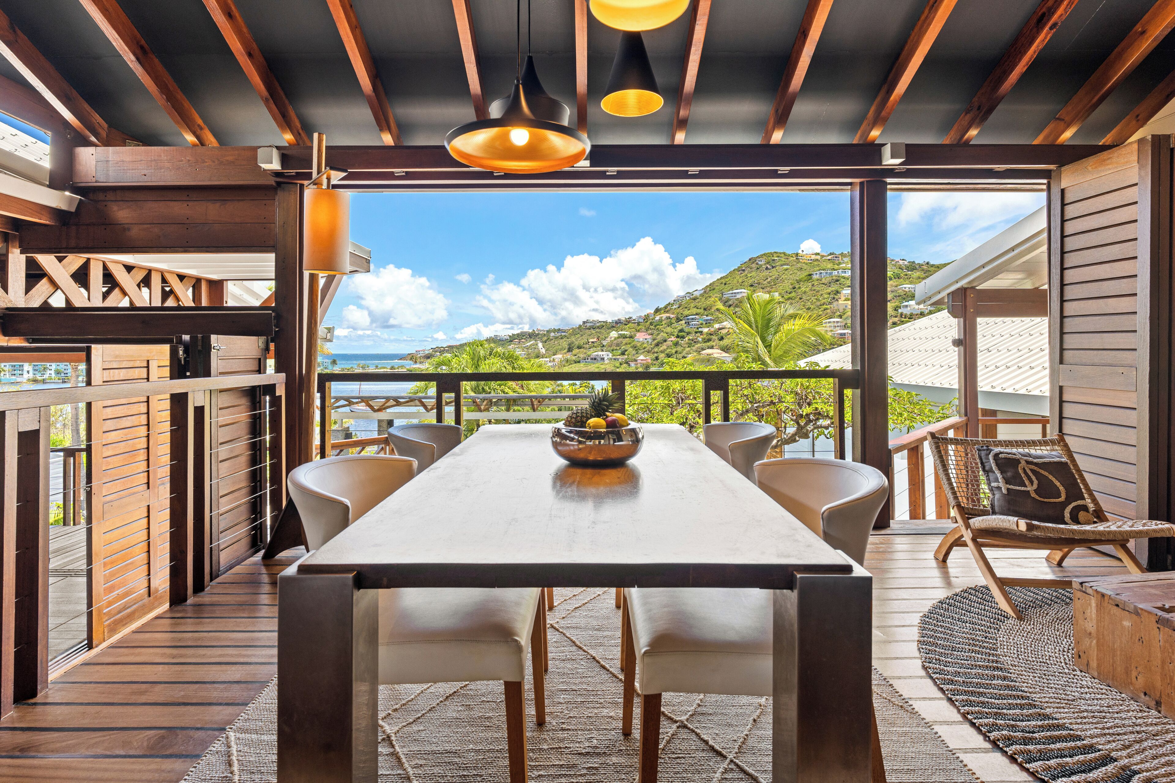 A dining area with a wooden table, chairs, and a view of a hillside.
