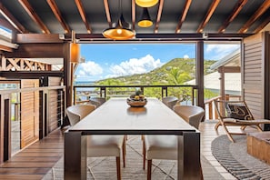 Un espace repas avec une table en bois, des chaises et une vue sur une colline.