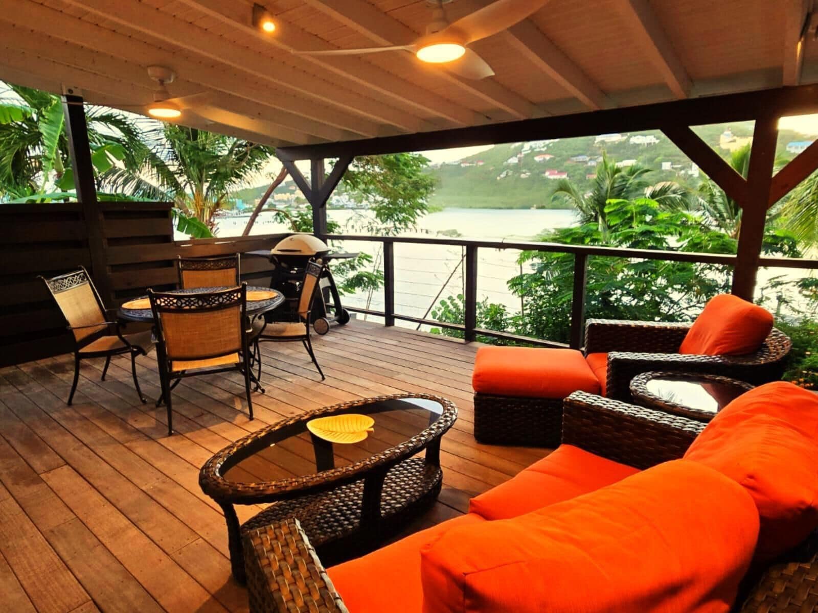Un espacio al aire libre techado con muebles de mimbre, una parrilla y vistas a un cuerpo de agua.