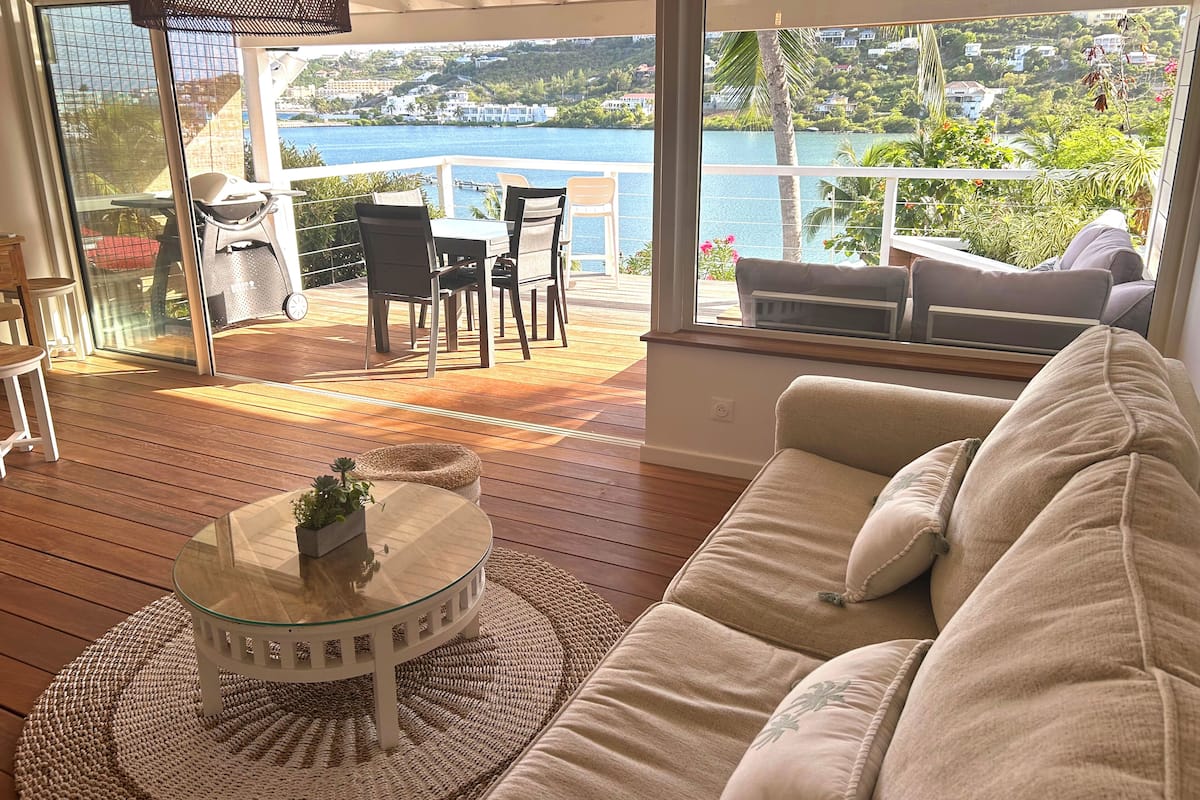 A spacious balcony with a wooden floor, a glass table, and a beige sofa.