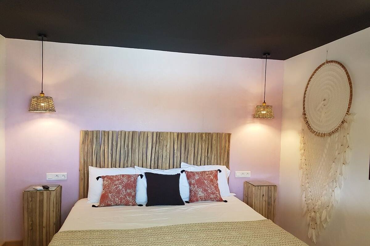 A bedroom with a bed, two bedside tables, a headboard, and wall decorations.