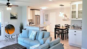 Un salon moderne comprenant un canapé, un coin repas, une cuisine et un ventilateur de plafond.