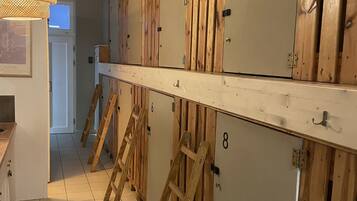 A row of wooden lockers with numbers, a tiled floor, and a hanging light fixture.