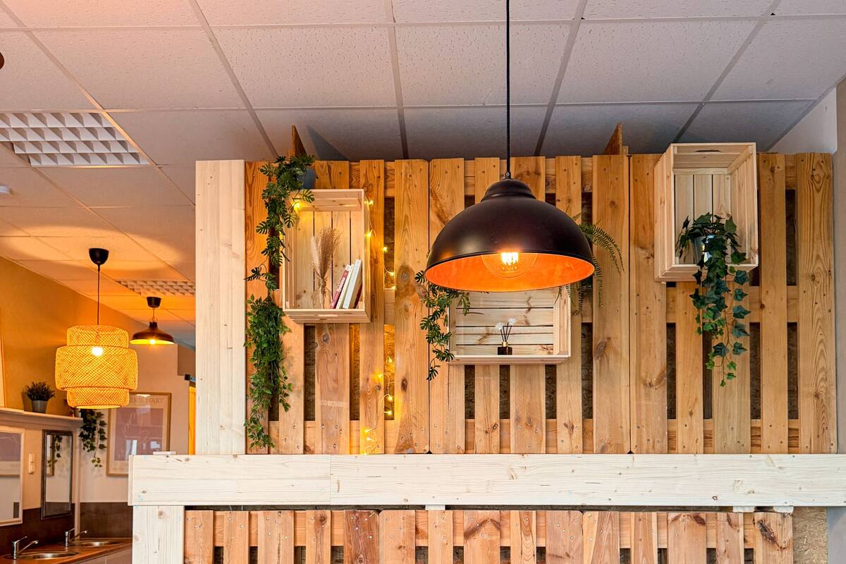 A modern interior with a wooden slat wall, a vibrant orange and pink sofa, and a black pendant light.