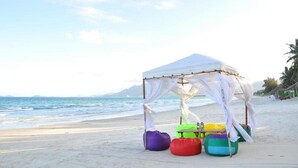 A beach with a white tent and colorful bean bags. - TTC Resort - Doc Let (Ninh Hoa)