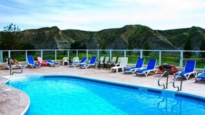 A swimming pool with blue lounge chairs and a view of mountains in the background. - Paradise Canyon Golf Resort (Lethbridge)