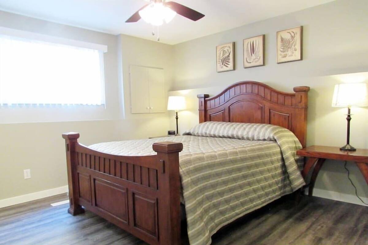 A bedroom with a wooden bed, a ceiling fan, and three wall-mounted lamps.
