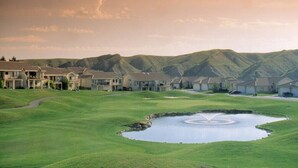 A golf course with a pond, surrounded by houses with a mountainous backdrop. - Paradise Canyon Golf Resort (Lethbridge)