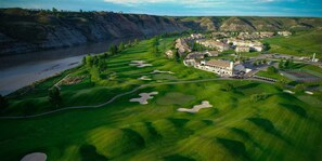 An aerial view of a golf course with a clubhouse, sand bunkers, and a river. - Paradise Canyon Golf Resort (Lethbridge)