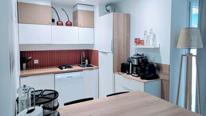 A modern kitchen with wooden cabinets, a built-in stove, and a coffee maker. - F2 garage,terrace,wifi,near town hall/train station/richter (Montpellier)