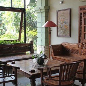 Een houten tafel met stoelen, een bankje en een potplant.