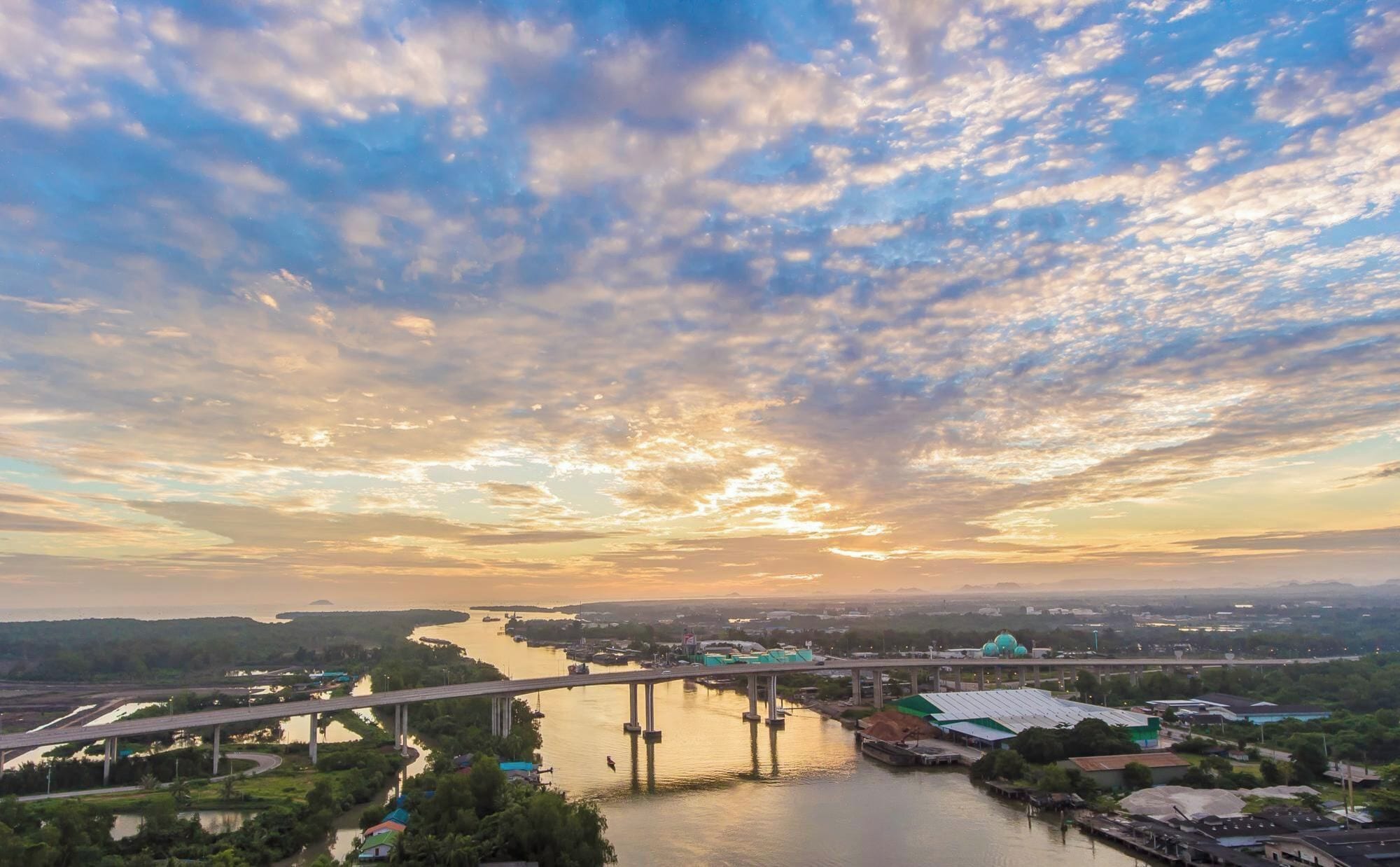 A river with a bridge, a body of water, and a distant cityscape.