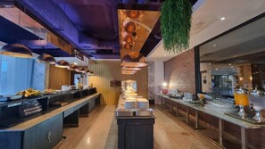 A modern kitchen with a central island, pendant lighting, and a brick wall. - CBD 2 Hotel (Surat Thani)